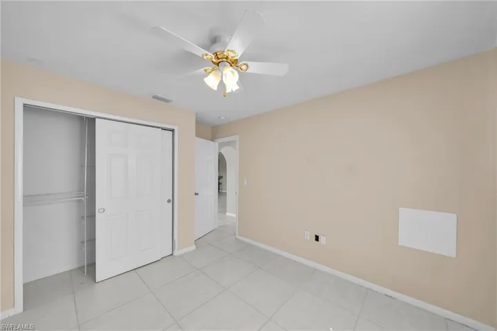 Unfurnished bedroom with ceiling fan, a closet, and light tile patterned floors