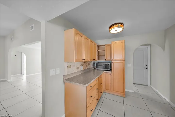 Kitchen featuring decorative backsplash, light brown cabinetry, and light tile patterned floors