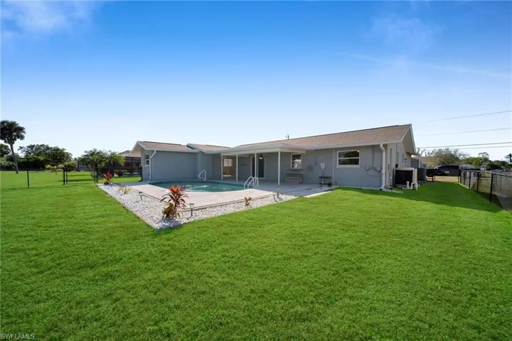 Back of house with a lawn, a sunroom, a fenced in pool, cooling unit, and a patio area