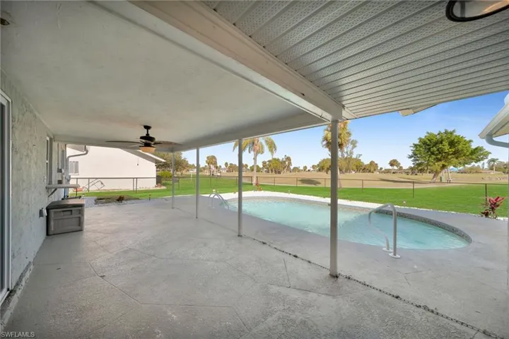 View of swimming pool featuring ceiling fan, a patio area, and a lawn