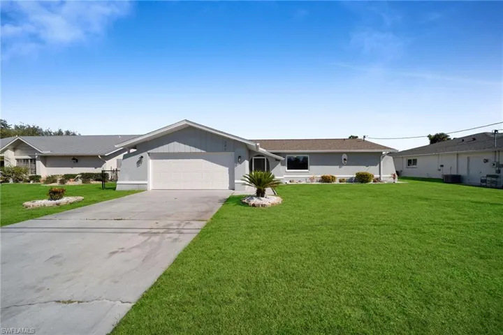 Ranch-style house featuring cooling unit, a garage, and a front lawn