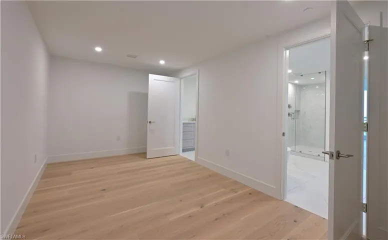 Unfurnished bedroom with light hardwood / wood-style floors and connected bathroom