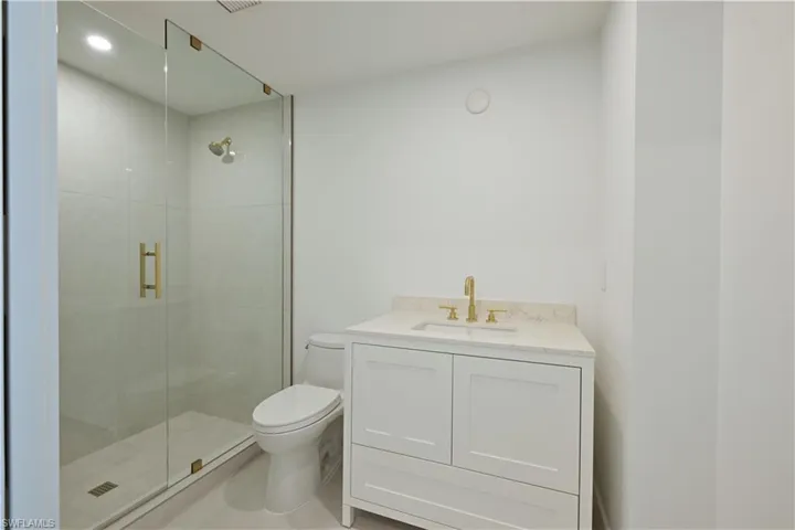 Bathroom featuring walk in shower, tile patterned floors, toilet, and vanity