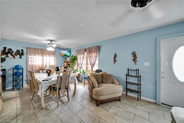 Dining room with ceiling fan, a textured ceiling, and light tile patterned flooring