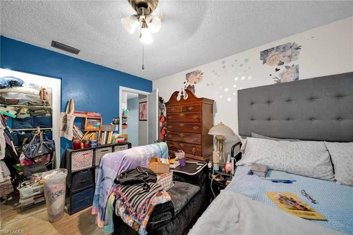 Bedroom with a textured ceiling, wood finished floors, ceiling fan, and a closet