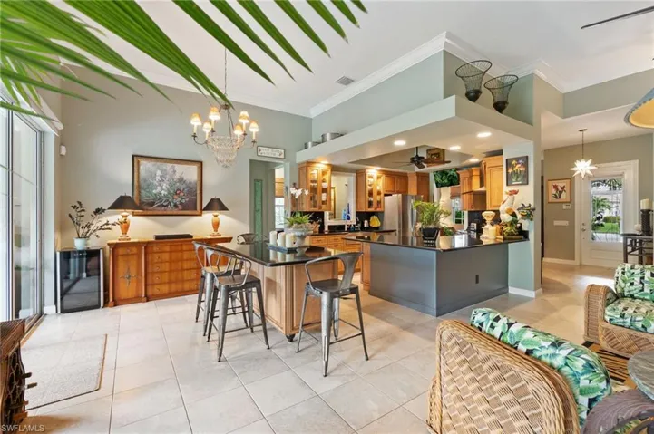 Kitchen with a chandelier, a peninsula, a ceiling fan, light tile patterned flooring, and brown cabinets
