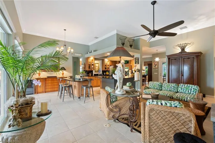 Living area with a chandelier, ornamental molding, light tile patterned floors, and a ceiling fan