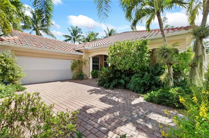 Mediterranean / spanish-style house with stucco siding, a tile roof, an attached garage, and decorative driveway