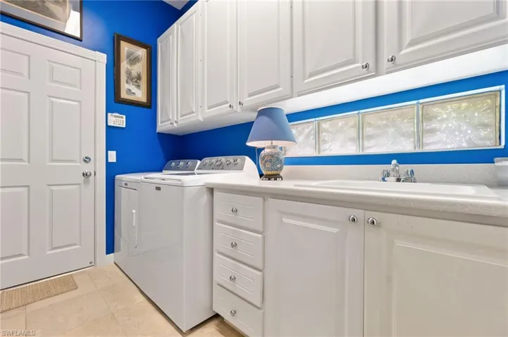Washroom featuring washer and dryer, light tile patterned floors, and cabinet space