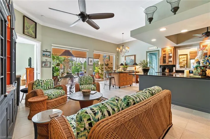 Living room featuring ceiling fan, crown molding, light tile patterned flooring, recessed lighting, and a chandelier