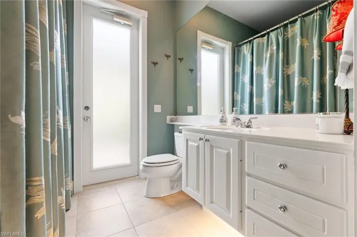 Bathroom with vanity, light tile patterned floors, and curtained shower