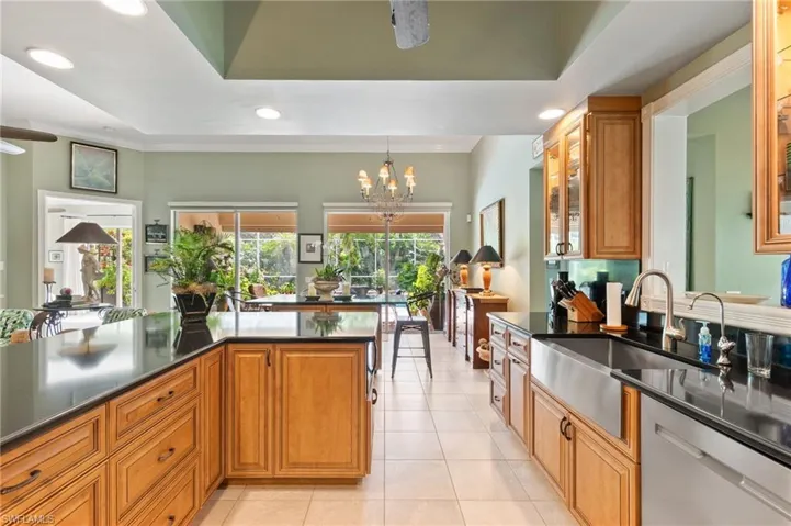 Kitchen featuring brown cabinets, stainless steel dishwasher, a ceiling fan, light tile patterned flooring, and recessed lighting