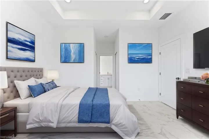 Bedroom with connected bathroom and a tray ceiling
