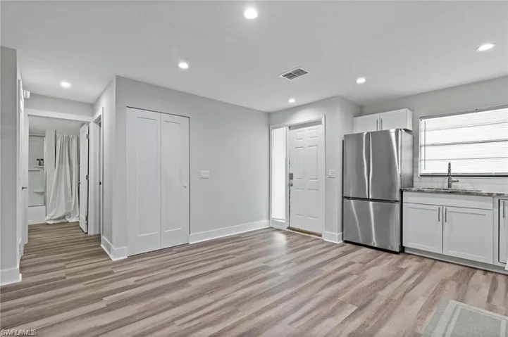 Kitchen featuring backsplash, stainless steel refrigerator, white cabinets, and light hardwood / wood-style floors