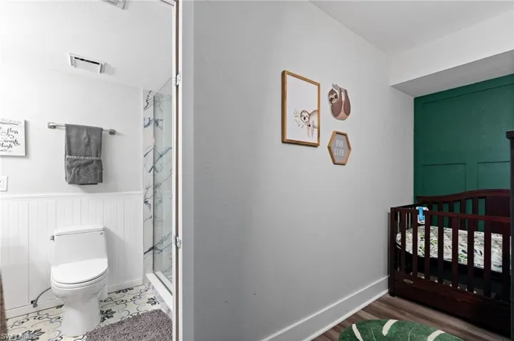 Bedroom with a nursery area and hardwood / wood-style floors
