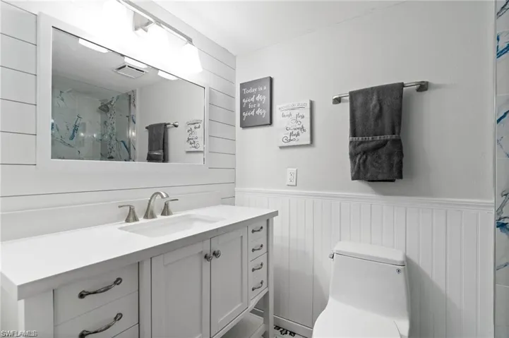 Bathroom with vanity, toilet, and a shower with shower door
