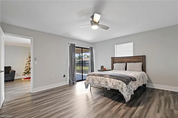 Bedroom featuring dark wood-type flooring, ceiling fan, and access to exterior