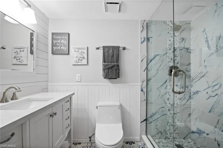 Bathroom featuring tile patterned flooring, vanity, toilet, and an enclosed shower