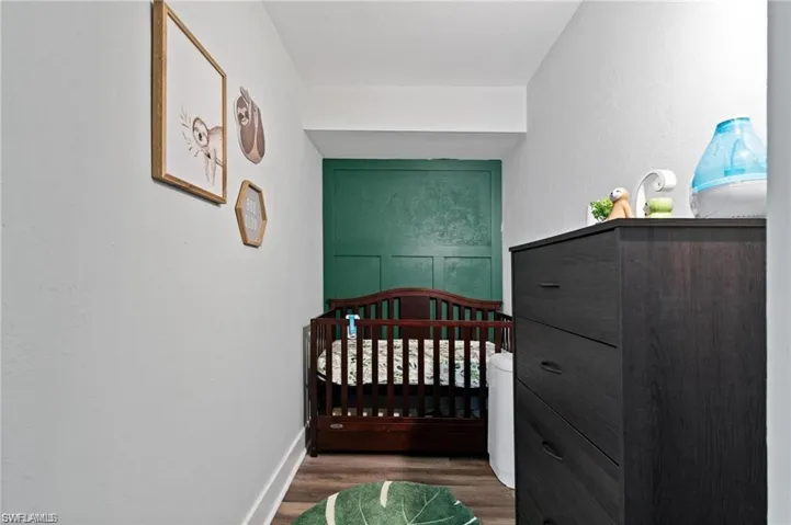 Bedroom with wood-type flooring and a crib