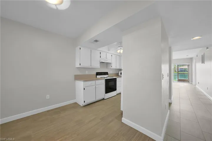 Kitchen with white electric range, white cabinetry, light wood-type flooring, and ceiling fan