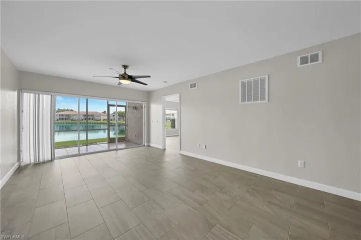 Tiled empty room featuring a water view and ceiling fan