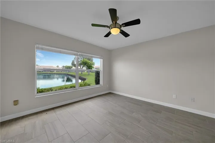 Empty room with a water view, ceiling fan, and plenty of natural light