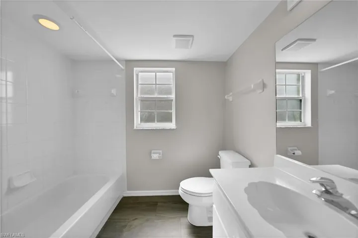 Full bathroom with a healthy amount of sunlight, tile patterned floors, vanity, and toilet
