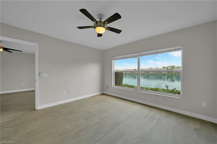 Unfurnished room featuring light tile patterned flooring, a water view, and ceiling fan