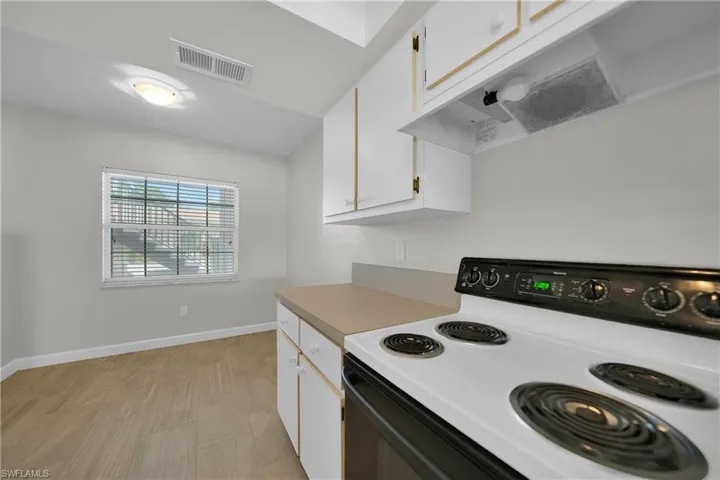 Kitchen featuring stove, white cabinets, and custom exhaust hood