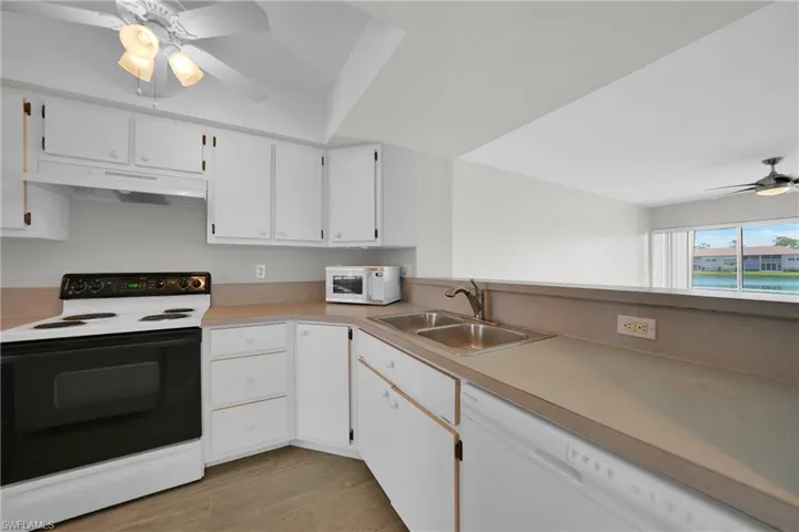 Kitchen featuring sink, ceiling fan, white appliances, and white cabinets