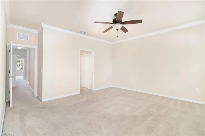 Empty room featuring light carpet, crown molding, and a ceiling fan