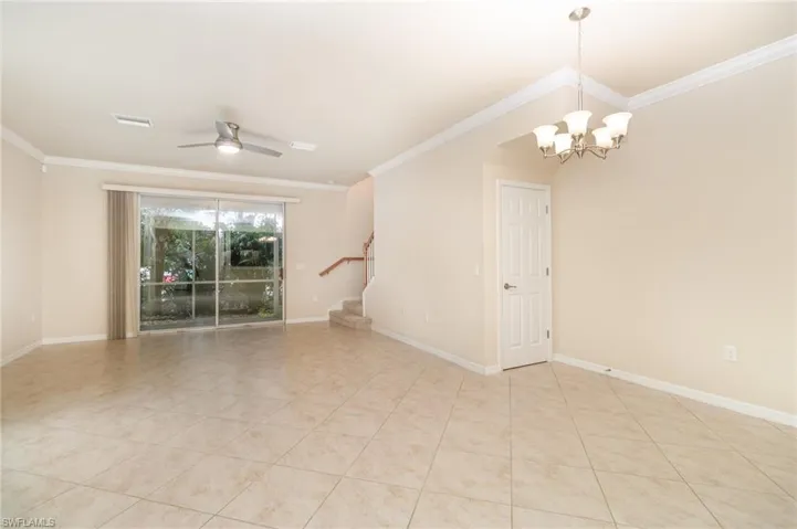 Spare room with stairs, crown molding, ceiling fan, a chandelier, and light tile patterned floors