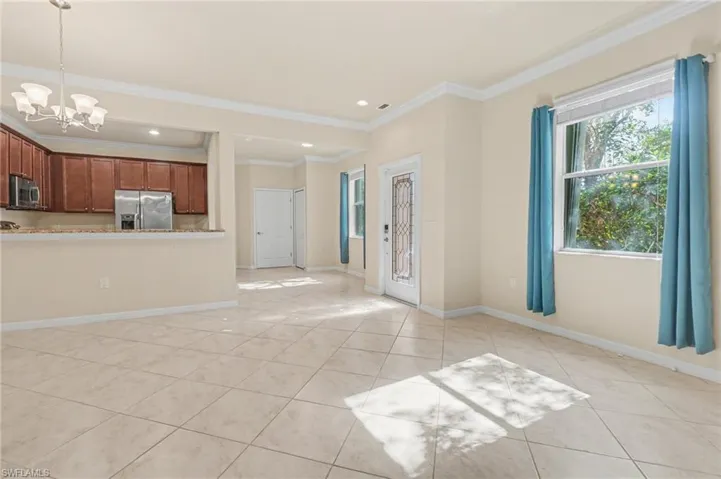 Unfurnished living room featuring a chandelier, ornamental molding, light tile patterned flooring, and recessed lighting