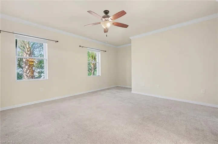 Spare room featuring ornamental molding, light colored carpet, and ceiling fan
