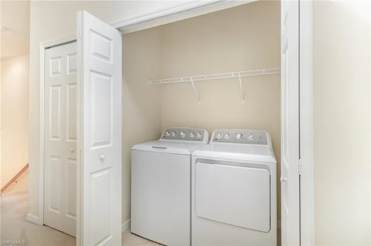 Laundry room featuring washing machine and dryer and light colored carpet