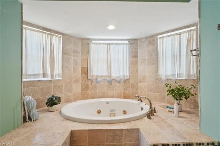 Full bathroom with a jetted tub and plenty of natural light
