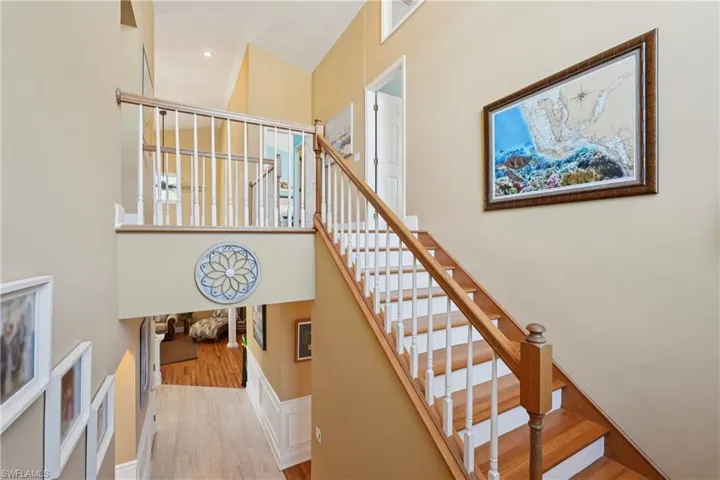 Staircase featuring wood finished floors, a high ceiling, and recessed lighting
