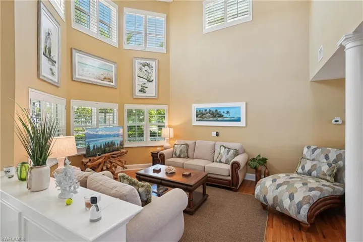 Living area with wood finished floors, healthy amount of natural light, and a high ceiling
