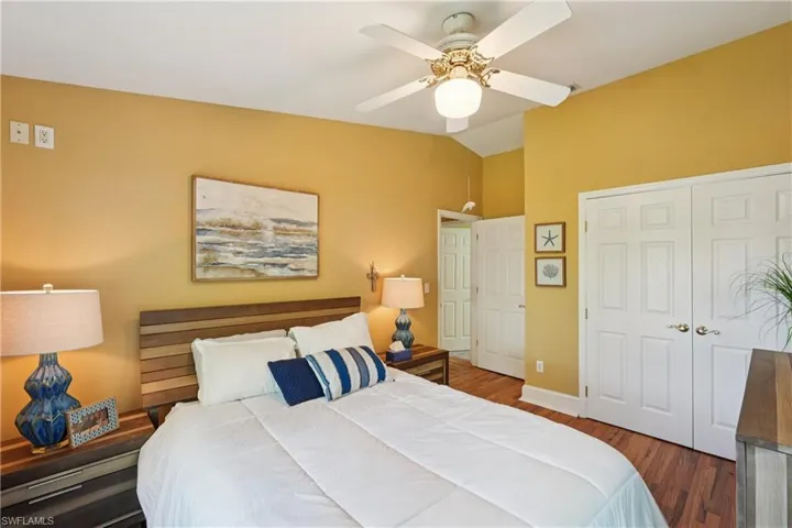 Bedroom with lofted ceiling, dark wood-style floors, ceiling fan, and a closet
