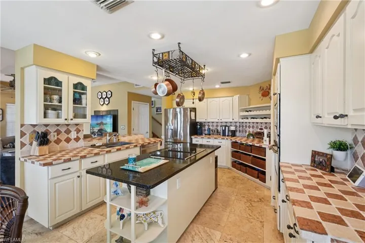 Kitchen with open shelves, backsplash, stainless steel refrigerator with ice dispenser, a kitchen island, and recessed lighting