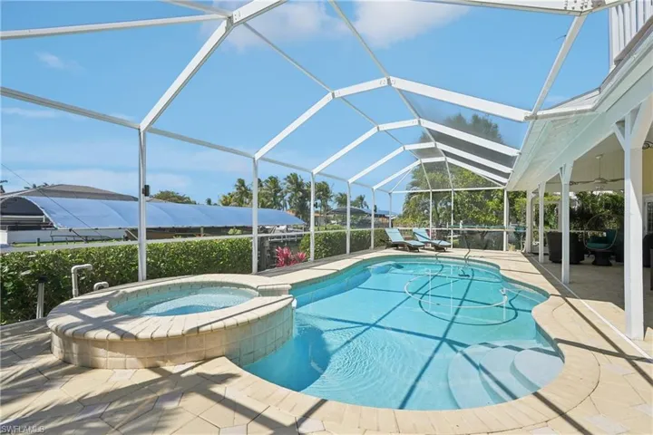 Integrated pool / hot tub with a sunroom, glass enclosure, and a patio