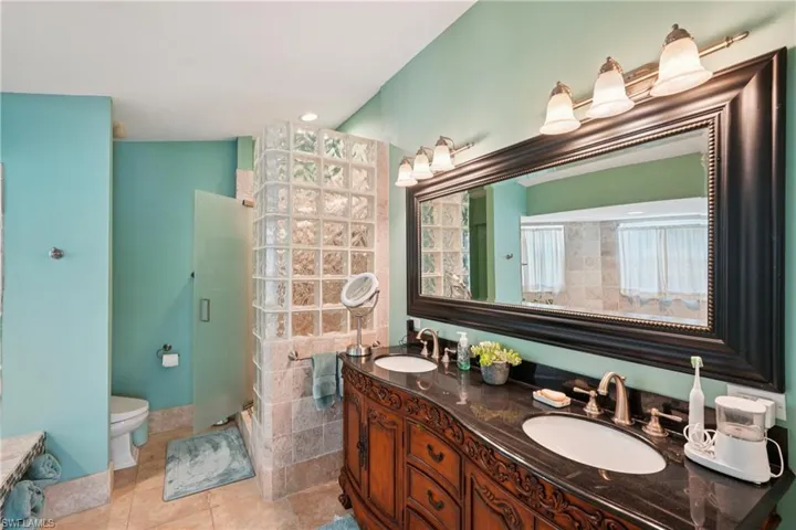 Full bathroom featuring double vanity, a stall shower, and light tile patterned floors