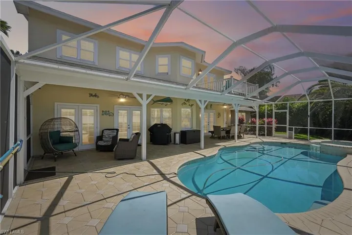 Pool at dusk featuring a lanai, a patio area, a sunroom, and french doors