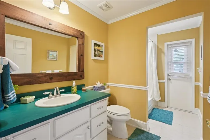 Full bathroom featuring crown molding, vanity, light tile patterned floors, and shower / bath combo