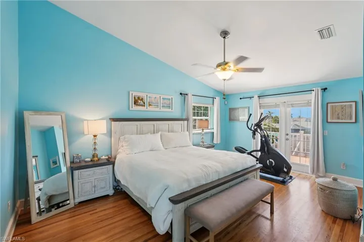 Bedroom featuring wood finished floors, access to outside, vaulted ceiling, ceiling fan, and french doors