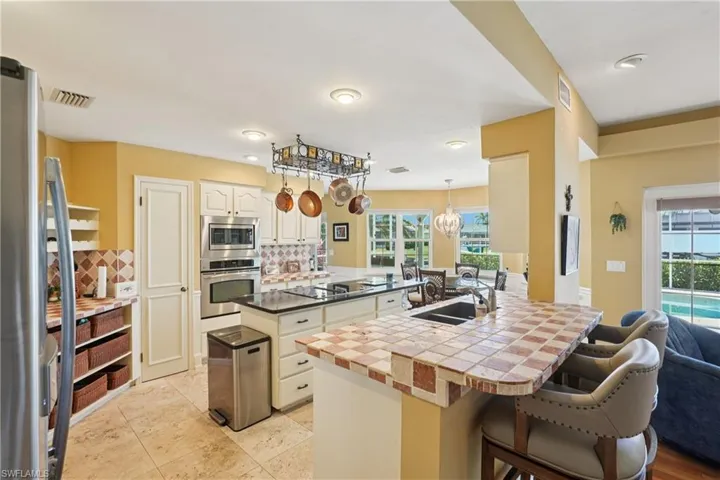 Kitchen featuring a kitchen breakfast bar, a peninsula, white cabinetry, stainless steel appliances, and backsplash
