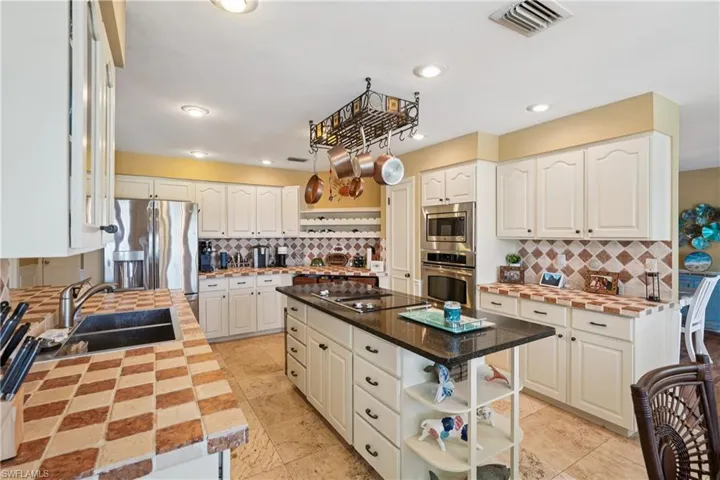 Kitchen featuring open shelves, stainless steel appliances, backsplash, a kitchen island, and white cabinets