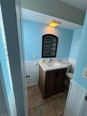 Bathroom featuring a wainscoted wall, vanity, and tile patterned flooring
