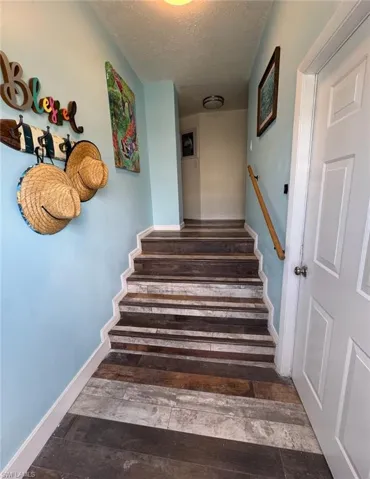 Stairs with a textured ceiling and wood finished floors