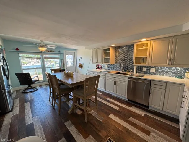 Kitchen with appliances with stainless steel finishes, dark wood-style flooring, light countertops, and backsplash